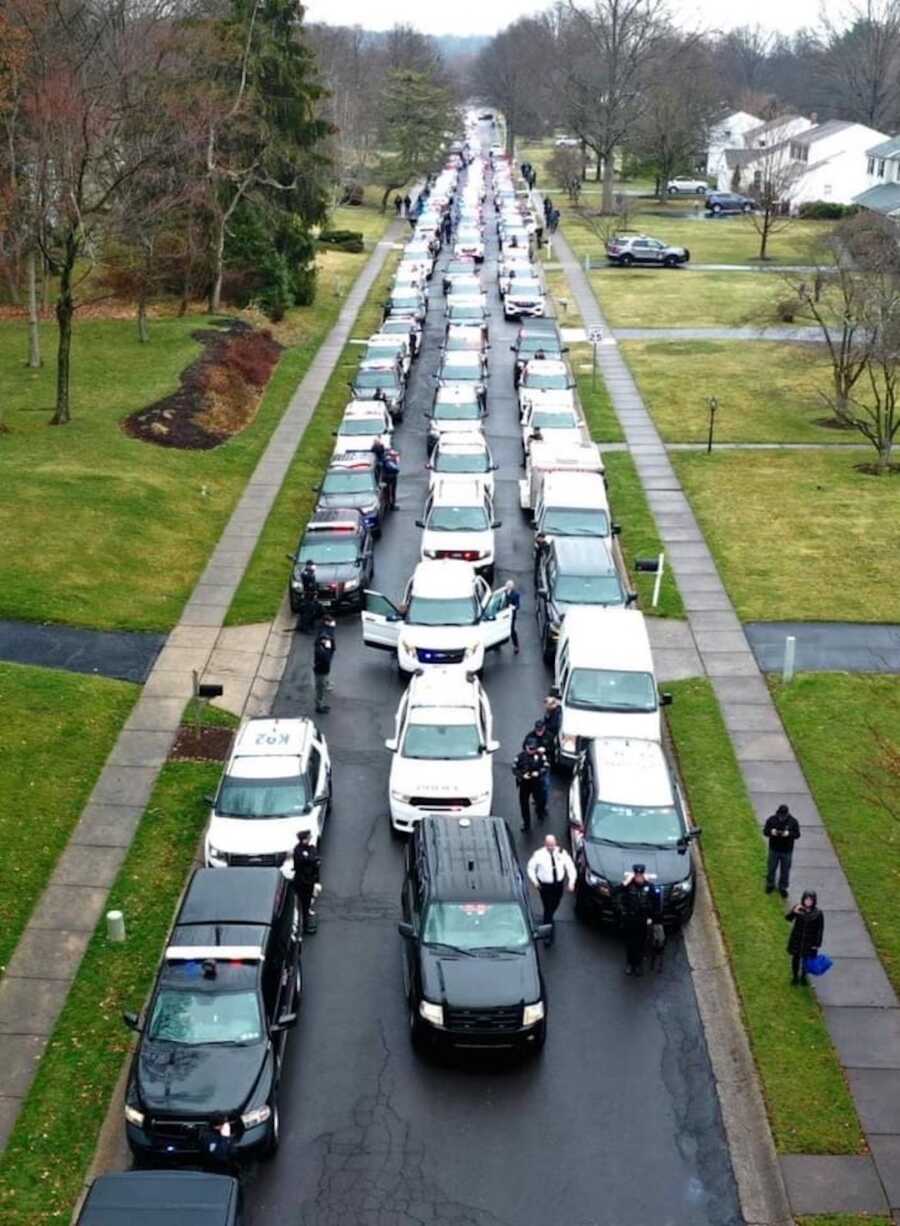 police cars lined up in procession to honor officer who died