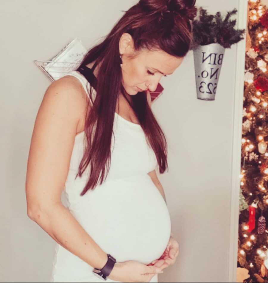woman in white dress holding pregnant belly
