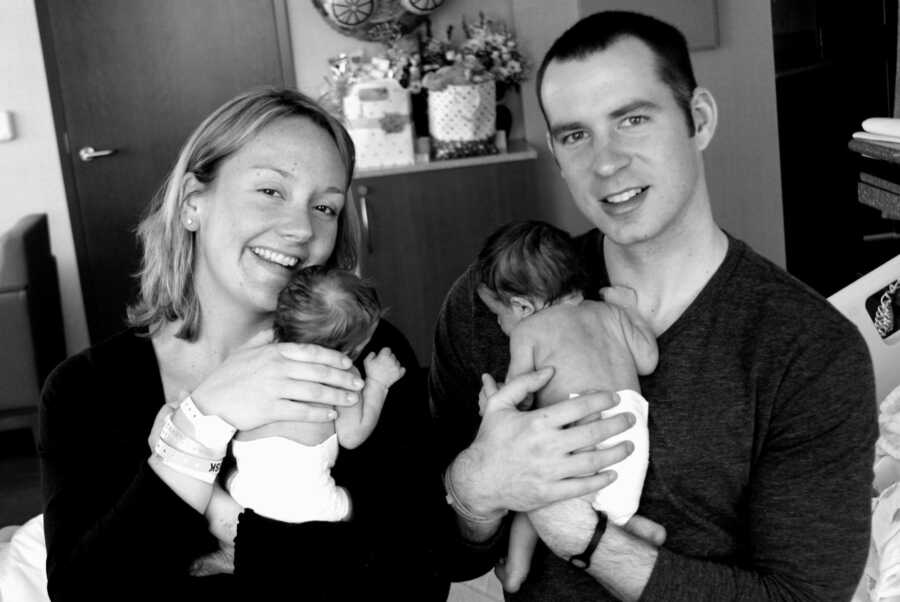 mom and dad hold their newborn twin girls