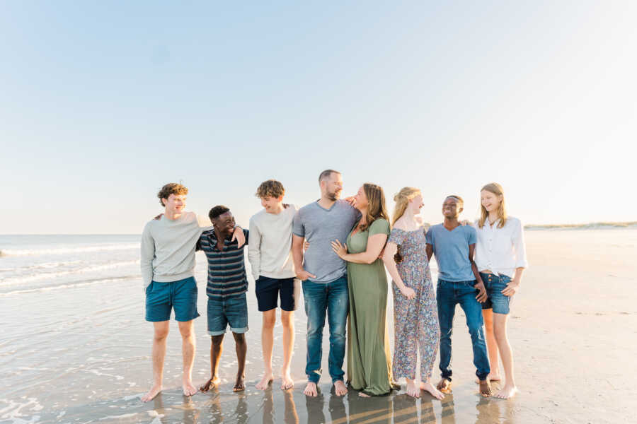 large family of eight gathers together on beach