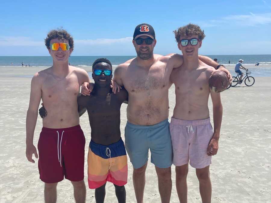 dad stands with his sons at the beach