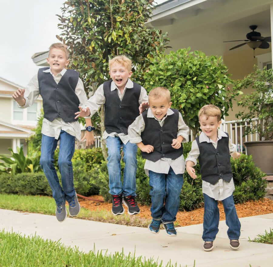 fours brothers wearing matching outfits jumping in the air and smiling