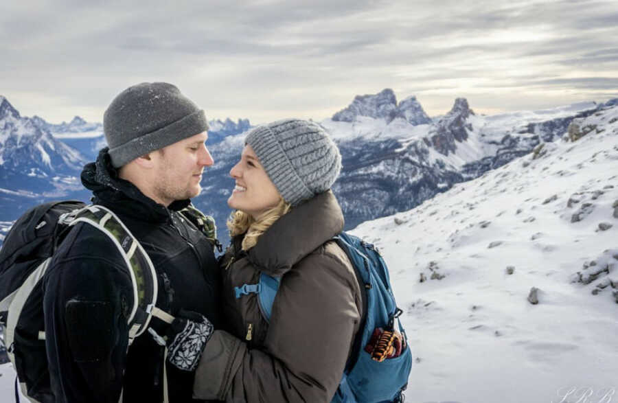 Military couple hiking up tall, snowy mountains