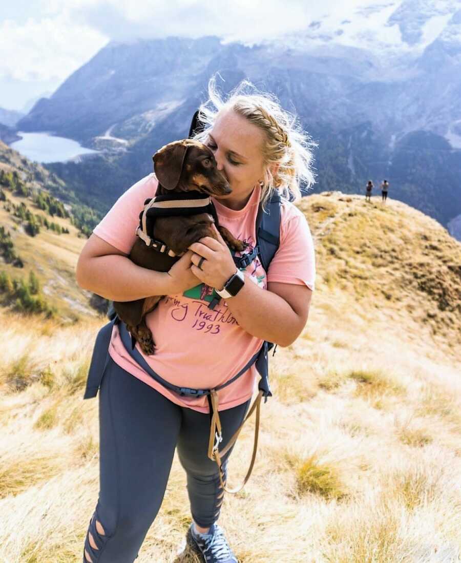 Military wife hiking up a big mountain with her small dog