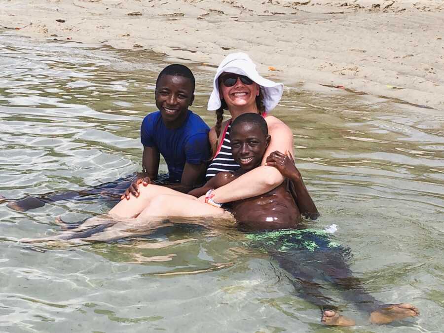 woman with her two adopted son sitting in the water