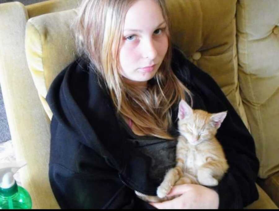 abused girl holding an orange kitten