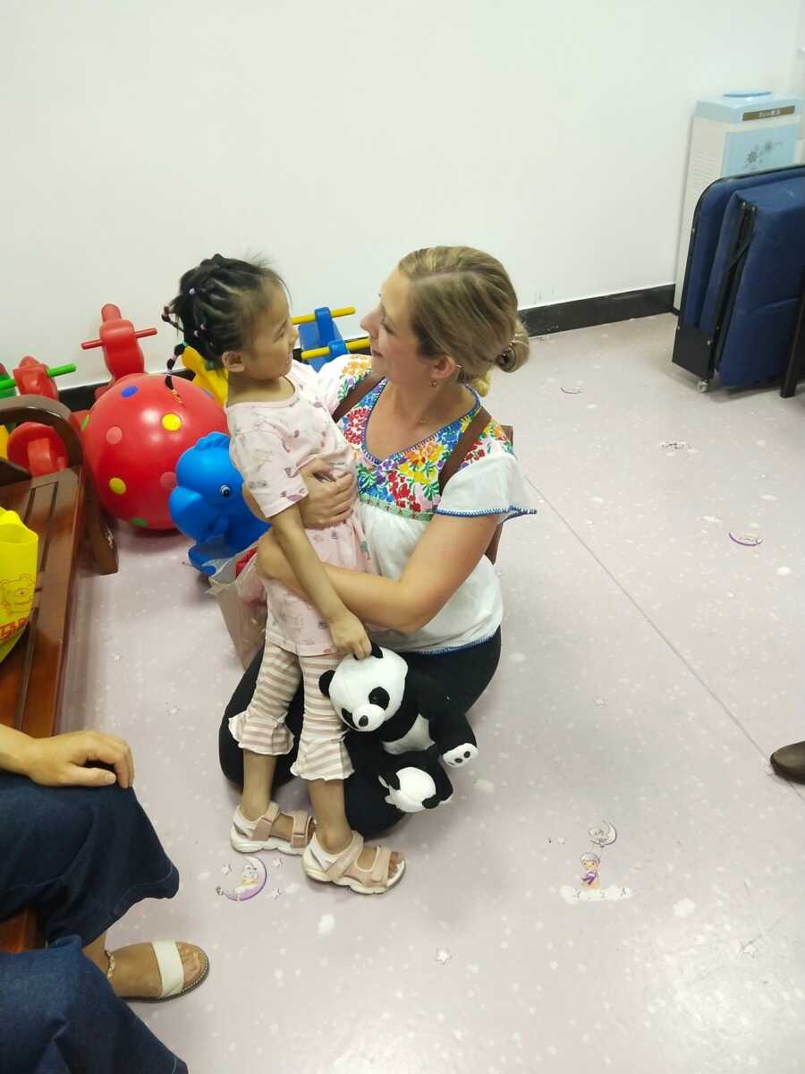 adoptive mom hugging internationally adopted daughter in playroom