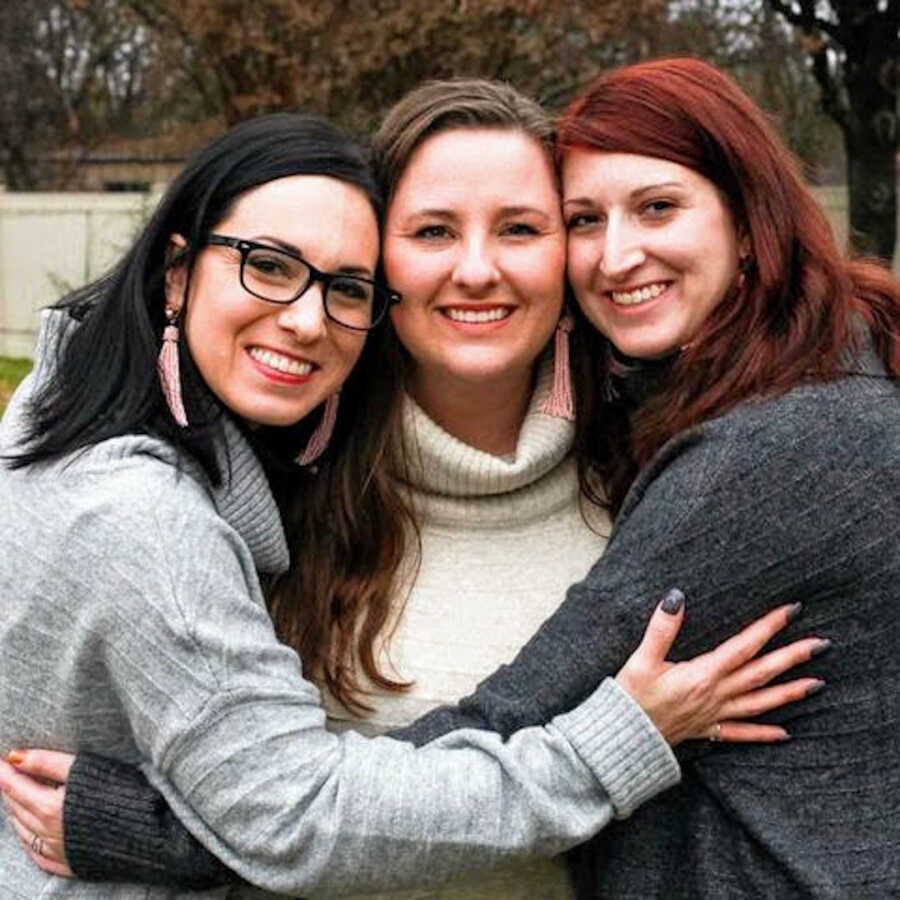 adult adoptee being hugged by her adopted sisters