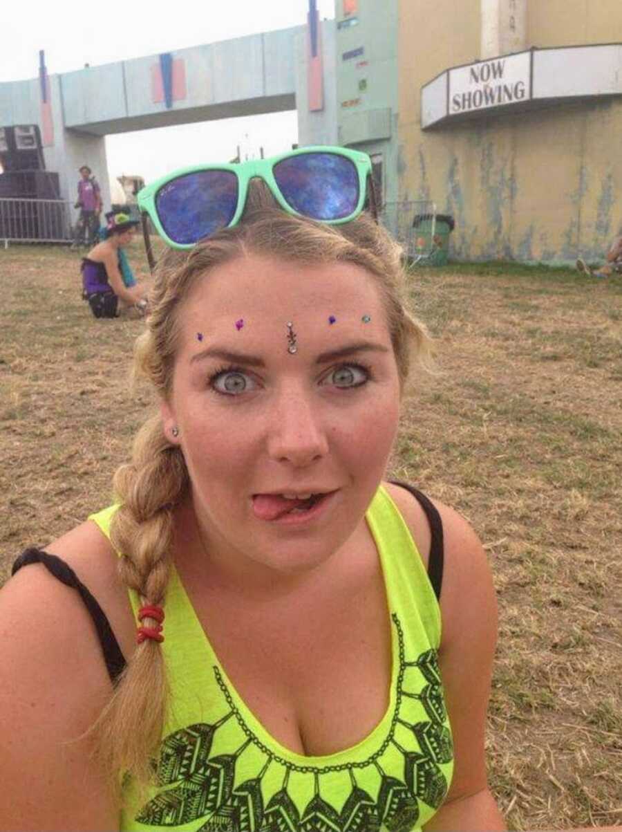 alcoholic at festival wearing face jewels and sticking tongue out
