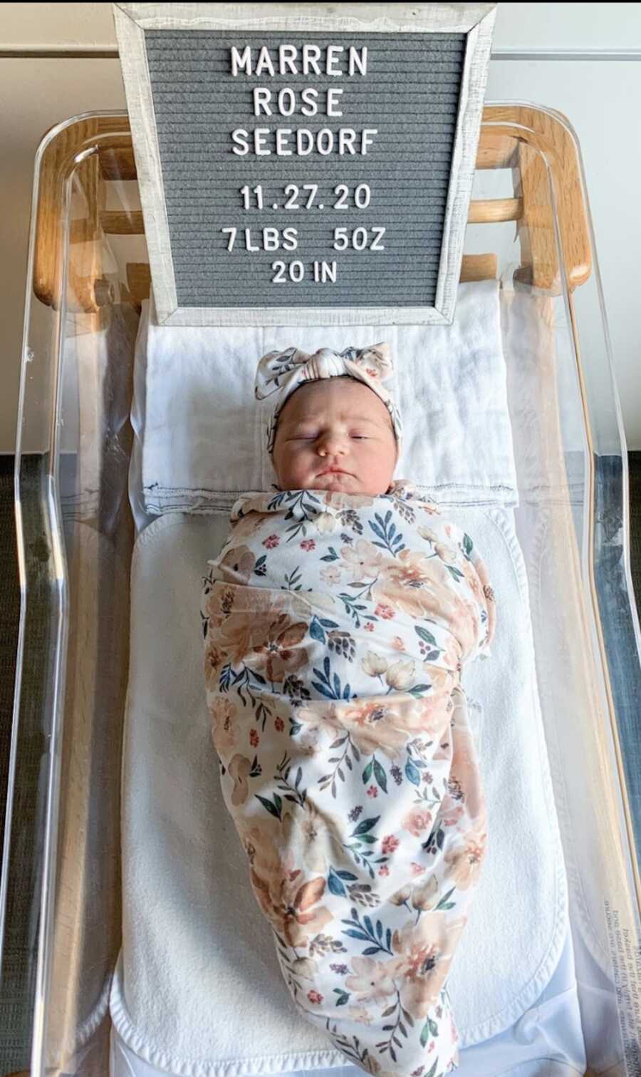 baby in basinet with nameplate over her