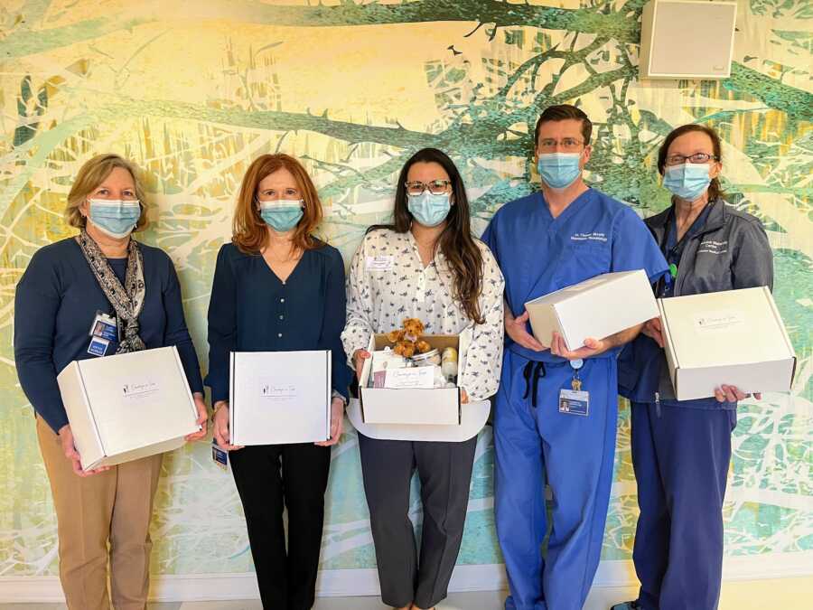 bereaved mother holding car packages with hospital staff