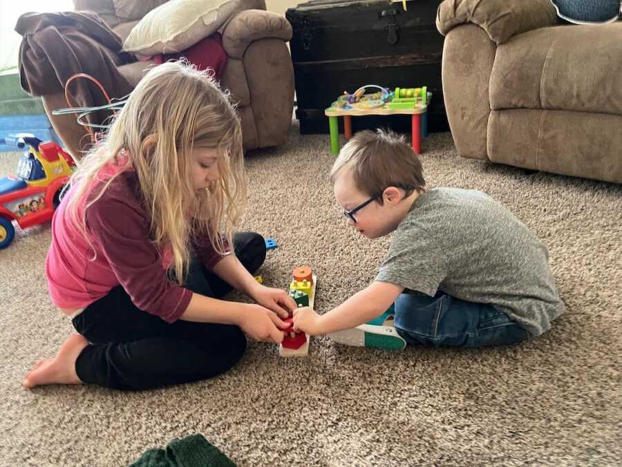 big sister playing with her younger brother with Down Syndrome