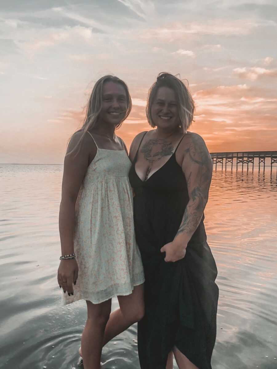 Birth mom takes picture with firstborn daughter at the beach at sunset.