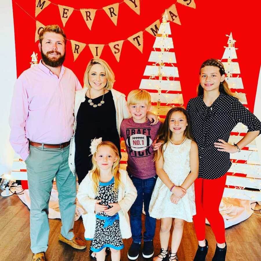 Blended family poses together in front of Christmas decorations 