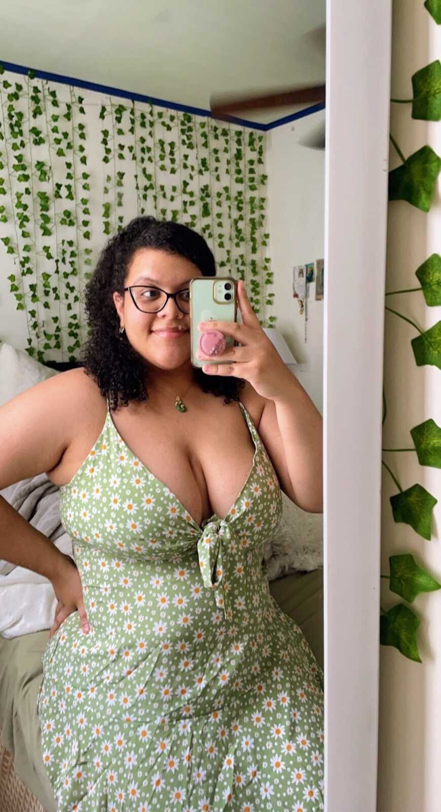 body positivity activist in green dress with white flowers taking a mirror selfie