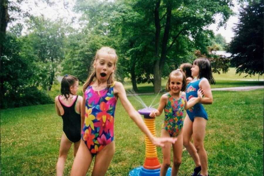 child in early stages of vitiligo playing in sprinkler with friends