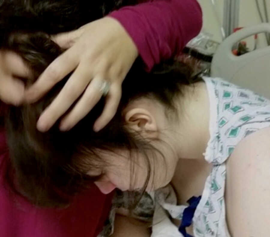 woman holds hair up of hospitalized chronically ill teen