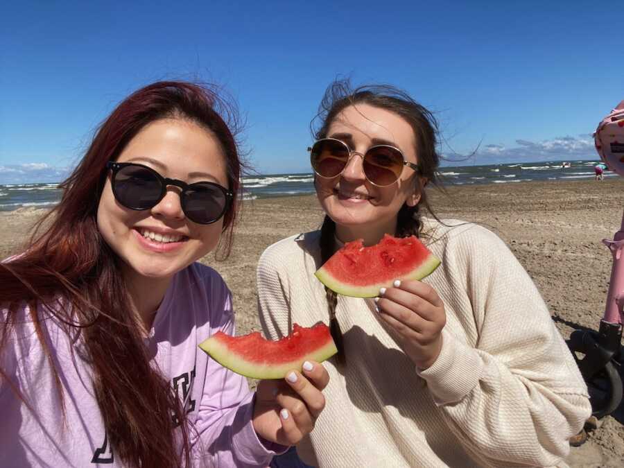 woman with friend holding slices of watermelon