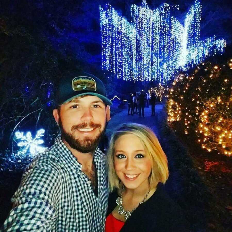 Couple takes a selfie in front of Christmas lights 