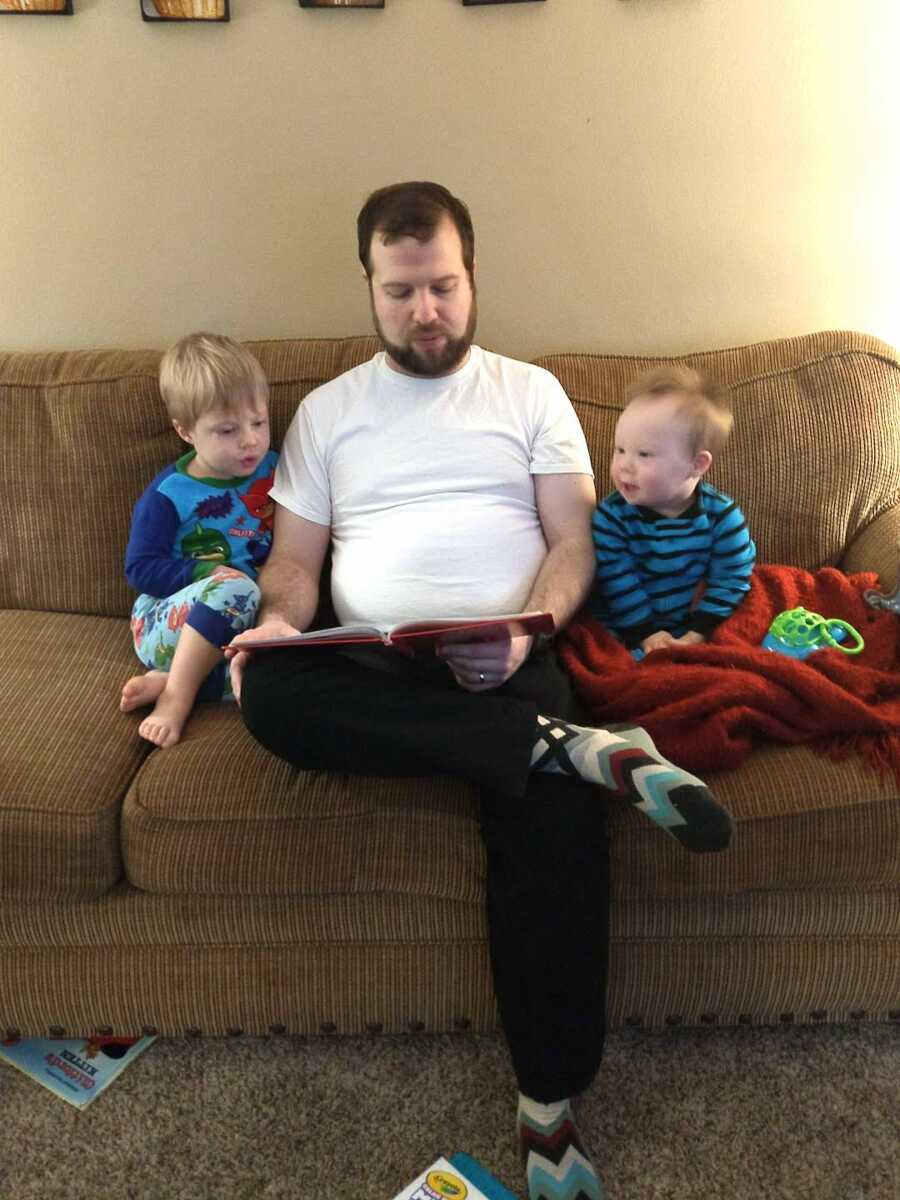 Dad sitting on couch with two sons reading a book