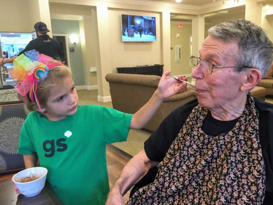 granddaughter spoon feeding grandpather