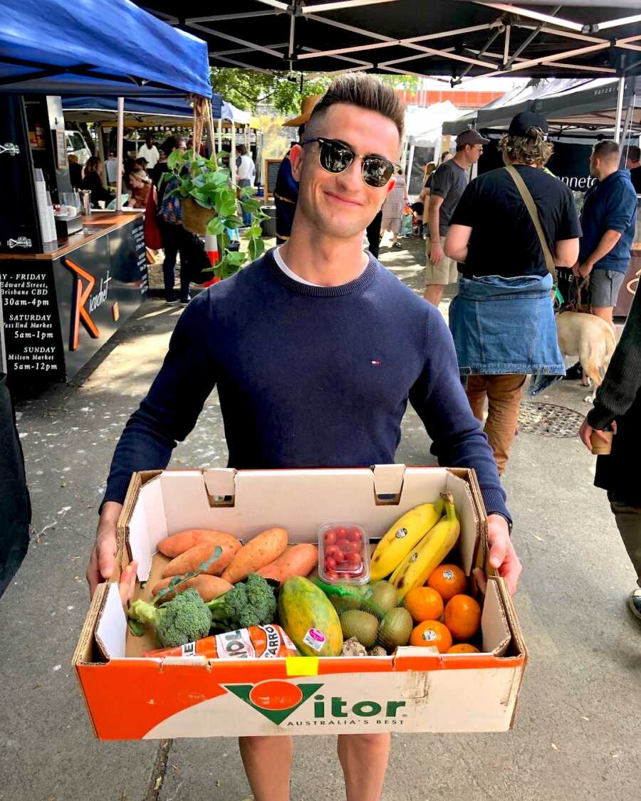man in recovery from eating disorder holds a box of vegtables