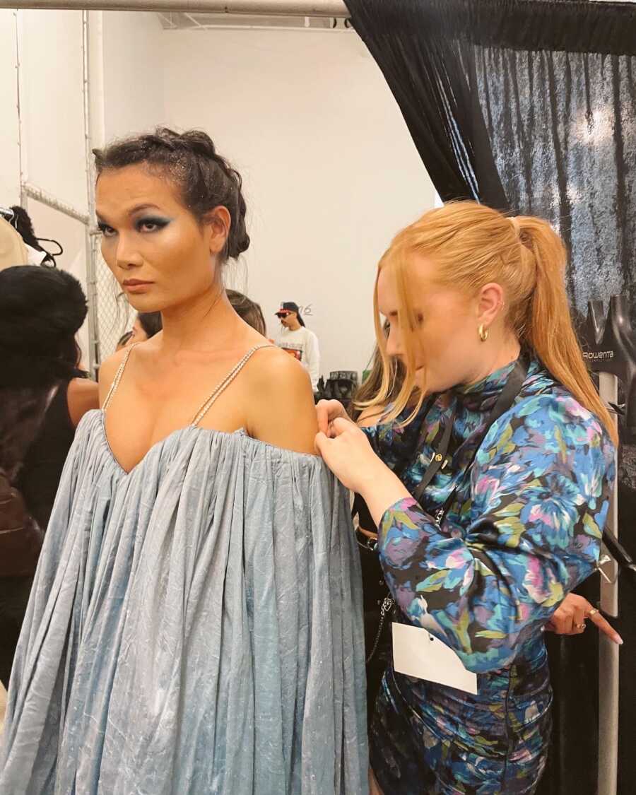 Fashion designer pins work on a model backstage