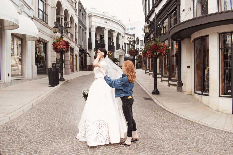 Fashion student adjusts the wedding dress she is posing 