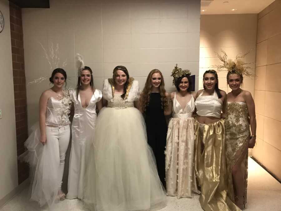 Fashion student poses with the models of her designs backstage