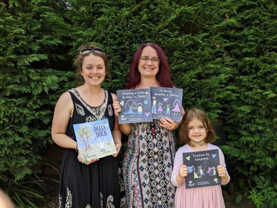 Author and family holding books in front of trees