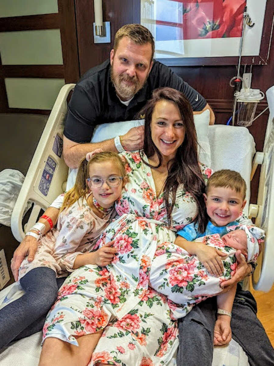 family in hospital bed holding newborn baby