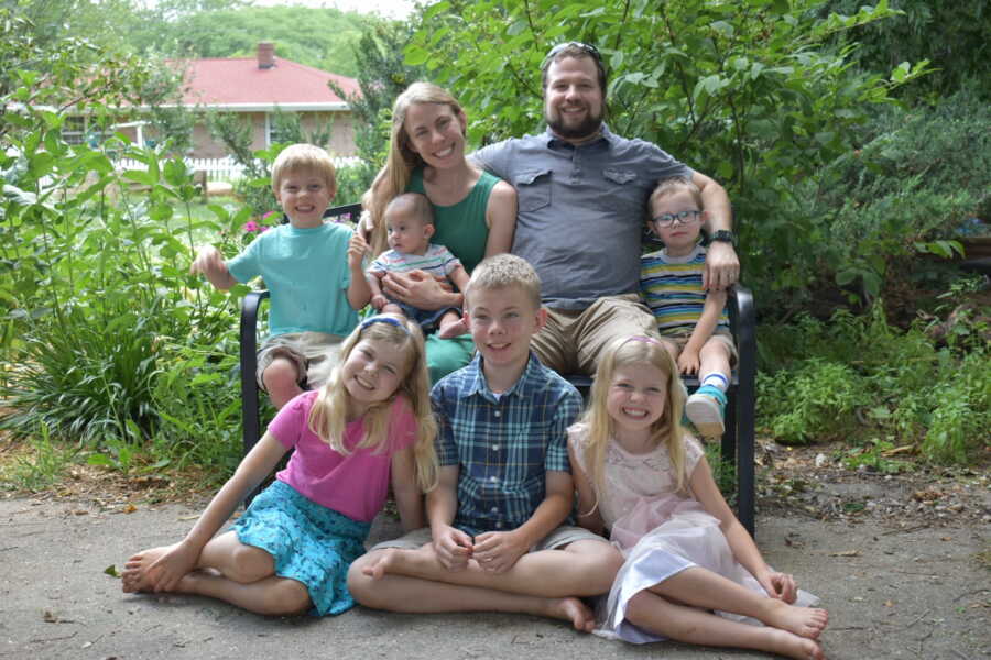 Family of eight sitting together on bench