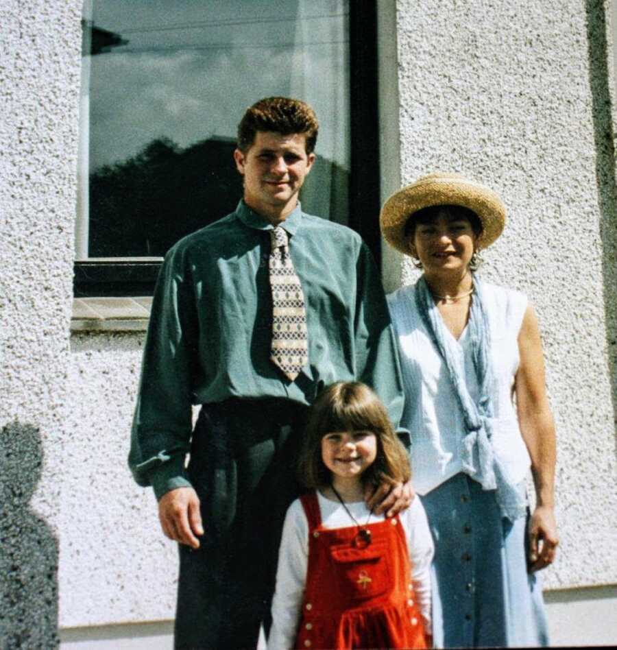 father, daughter, and mother standing together