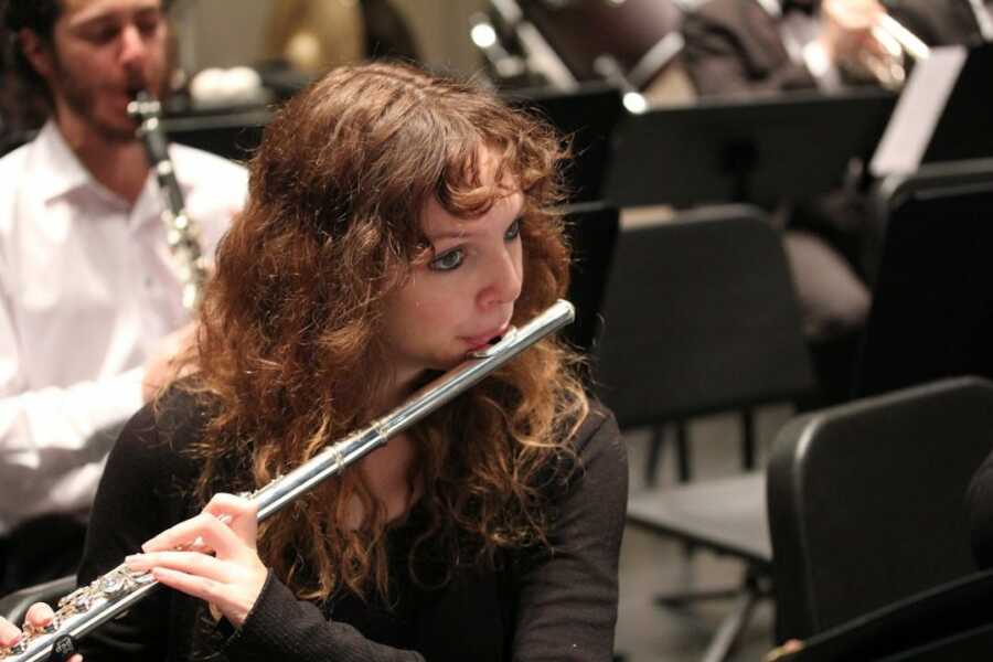 female flute player mid performance in orchestra concert