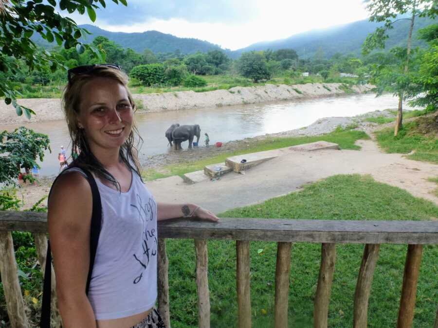 formerly abused mother on a deck overlooking field with elephants