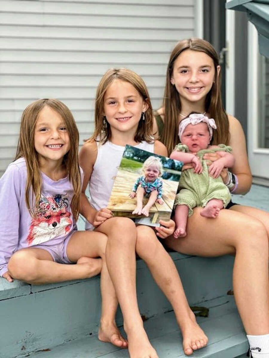 four sisters sitting on porch holding photo of their dead sister