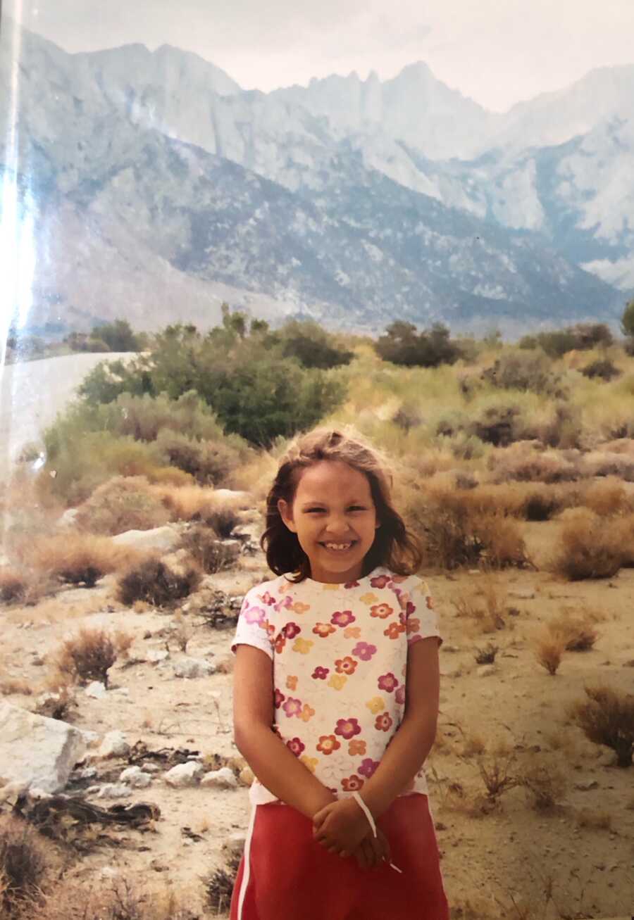 girl standing on plains with mountains behind her