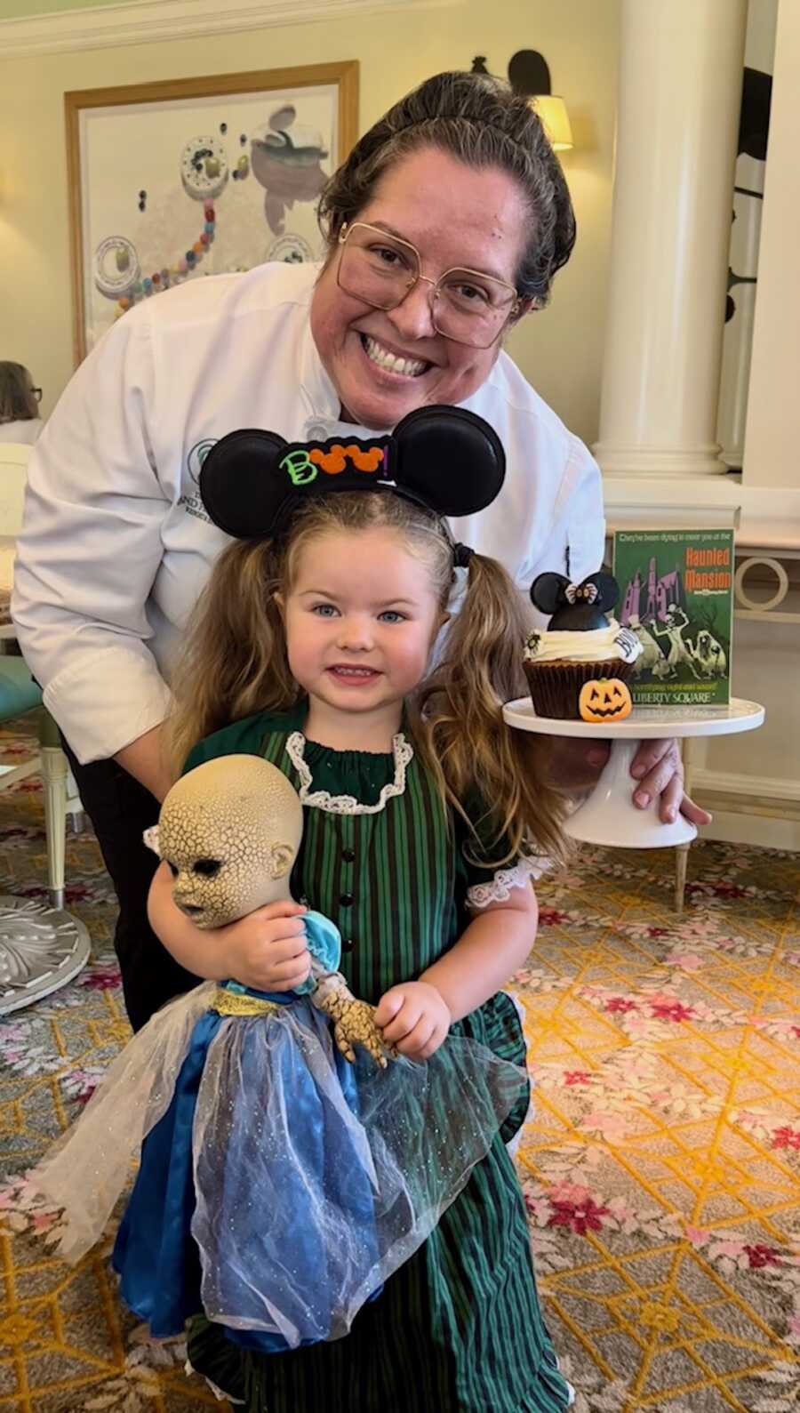 girl and creepy doll pose with disney world pastry chef
