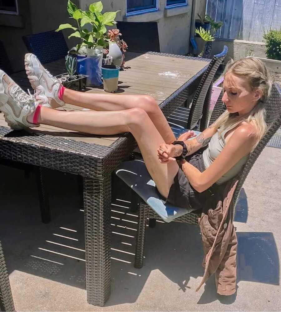 girl with eating disorder sitting at table with legs up