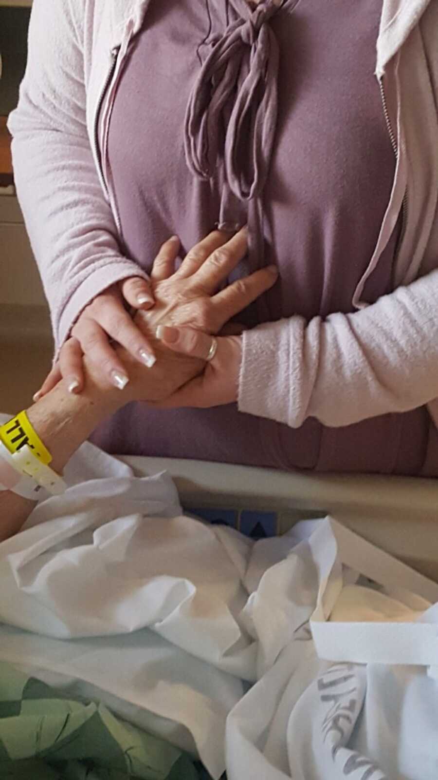 granddaughter holds her grandma's hand before she passes