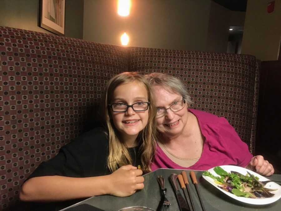 granddaughter sitting with Alzheimers grandmother at dinner