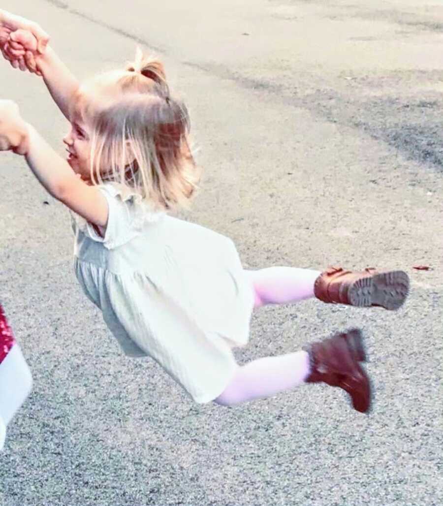 Happy toddler girl being swung by mom