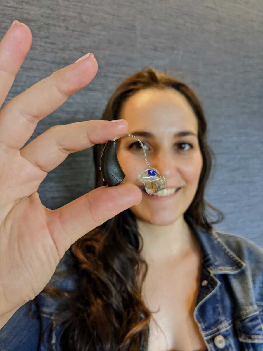 hearing impaired woman holding a hearing aid