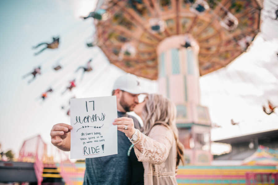 husband and wife holding paper stating 17 month infertility journey