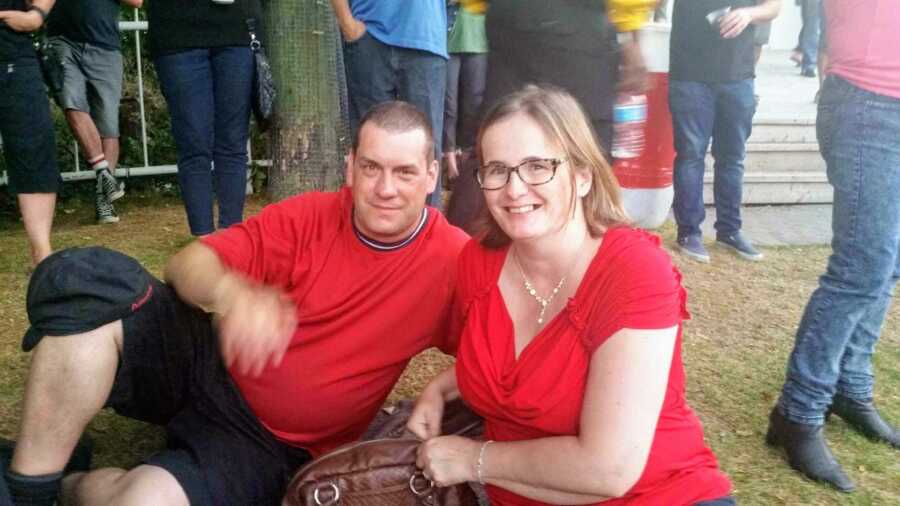 husband and wife sitting on the ground in red shirts