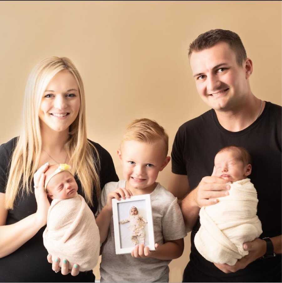 parents holding twin babies with toddler son holding dead daughter's photo