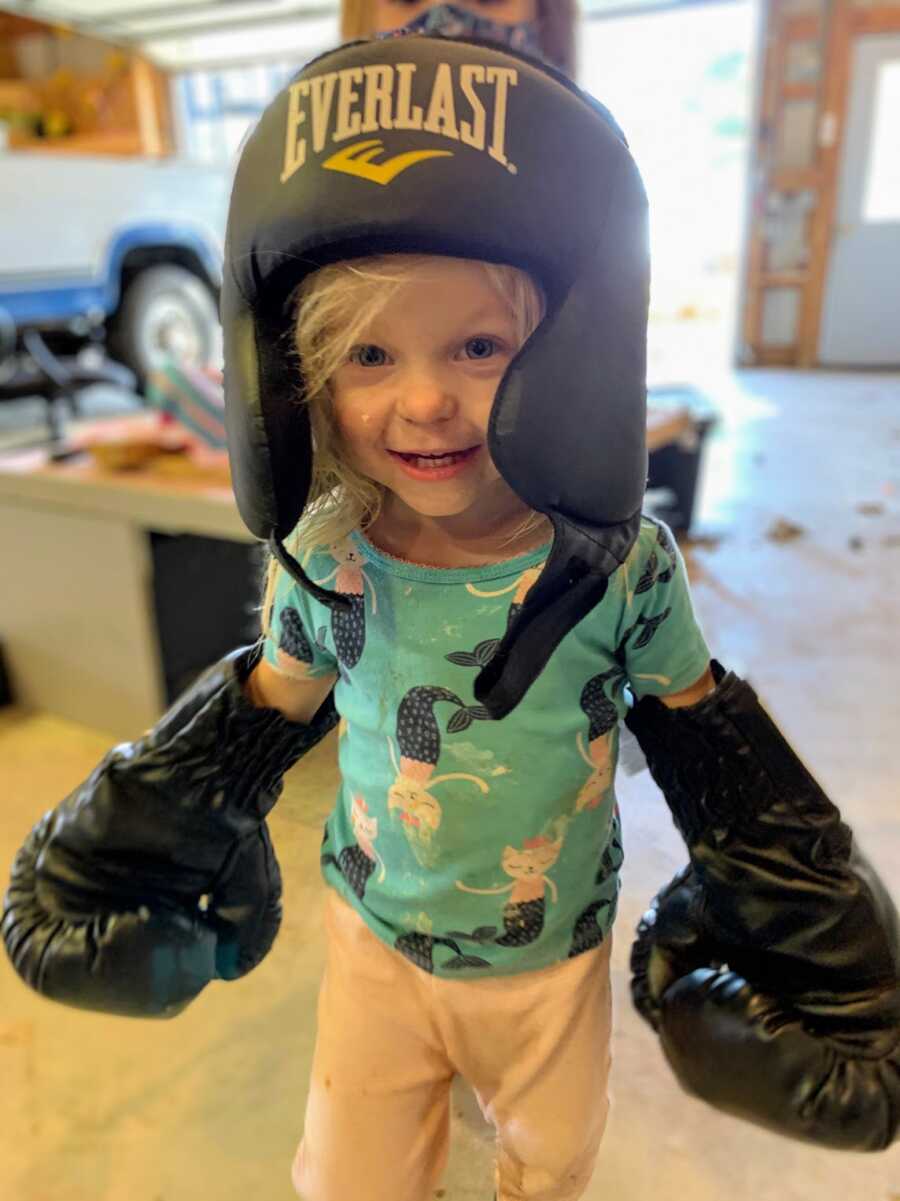 infant daughter wearing boxing gloves and a foam helmet
