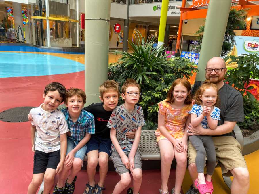 Family of six poses in front of a mall
