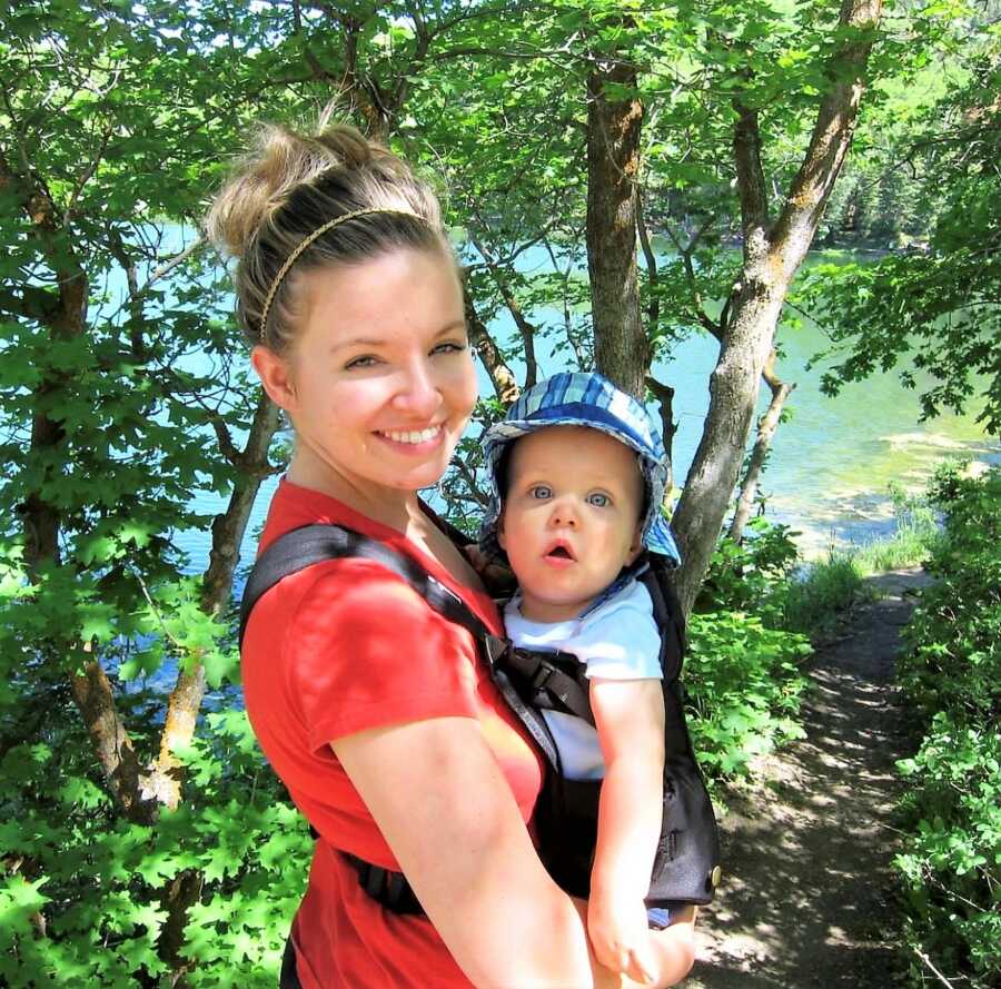 Mom holding her son in a baby carrier during a walk outdoors 