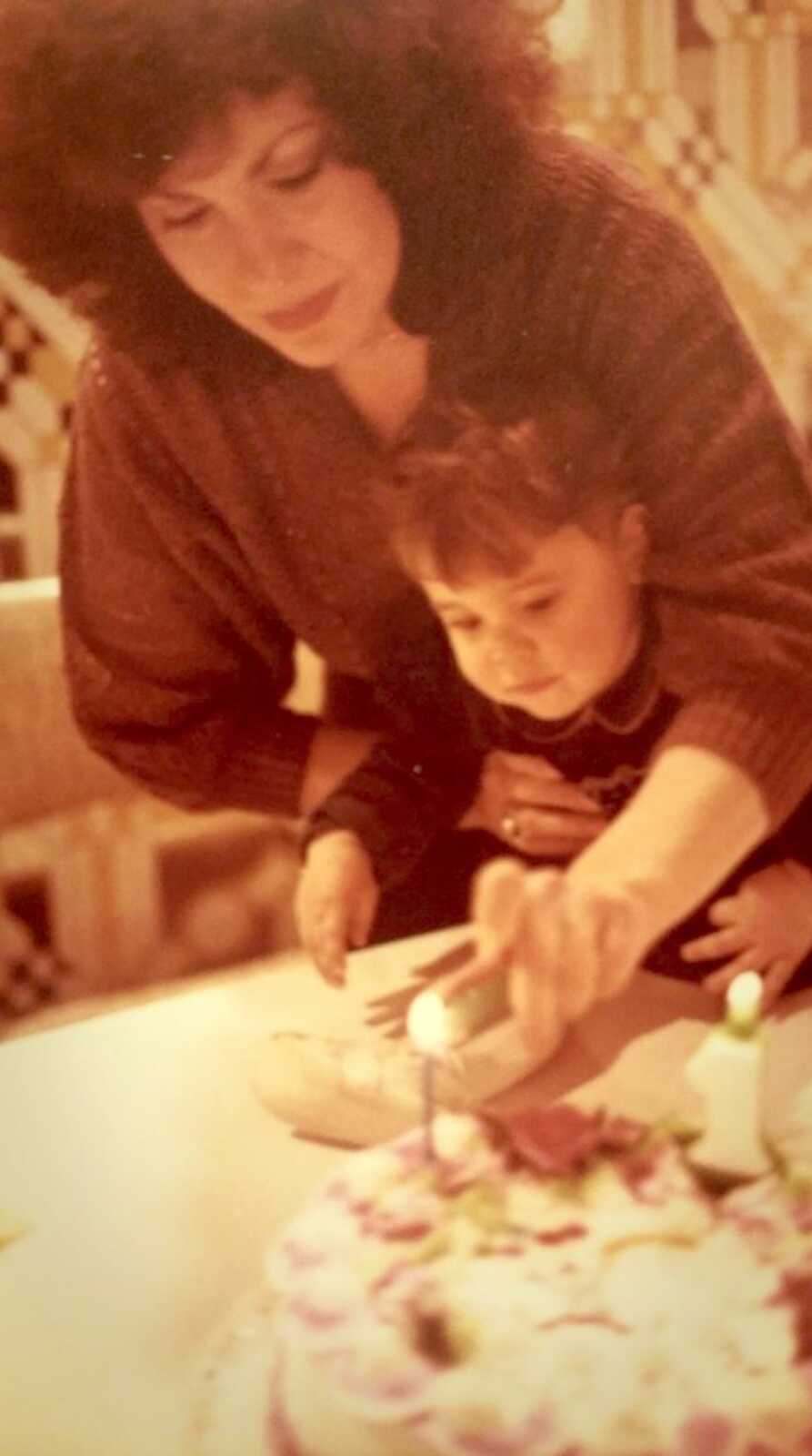 mom holding daughter cutting cake